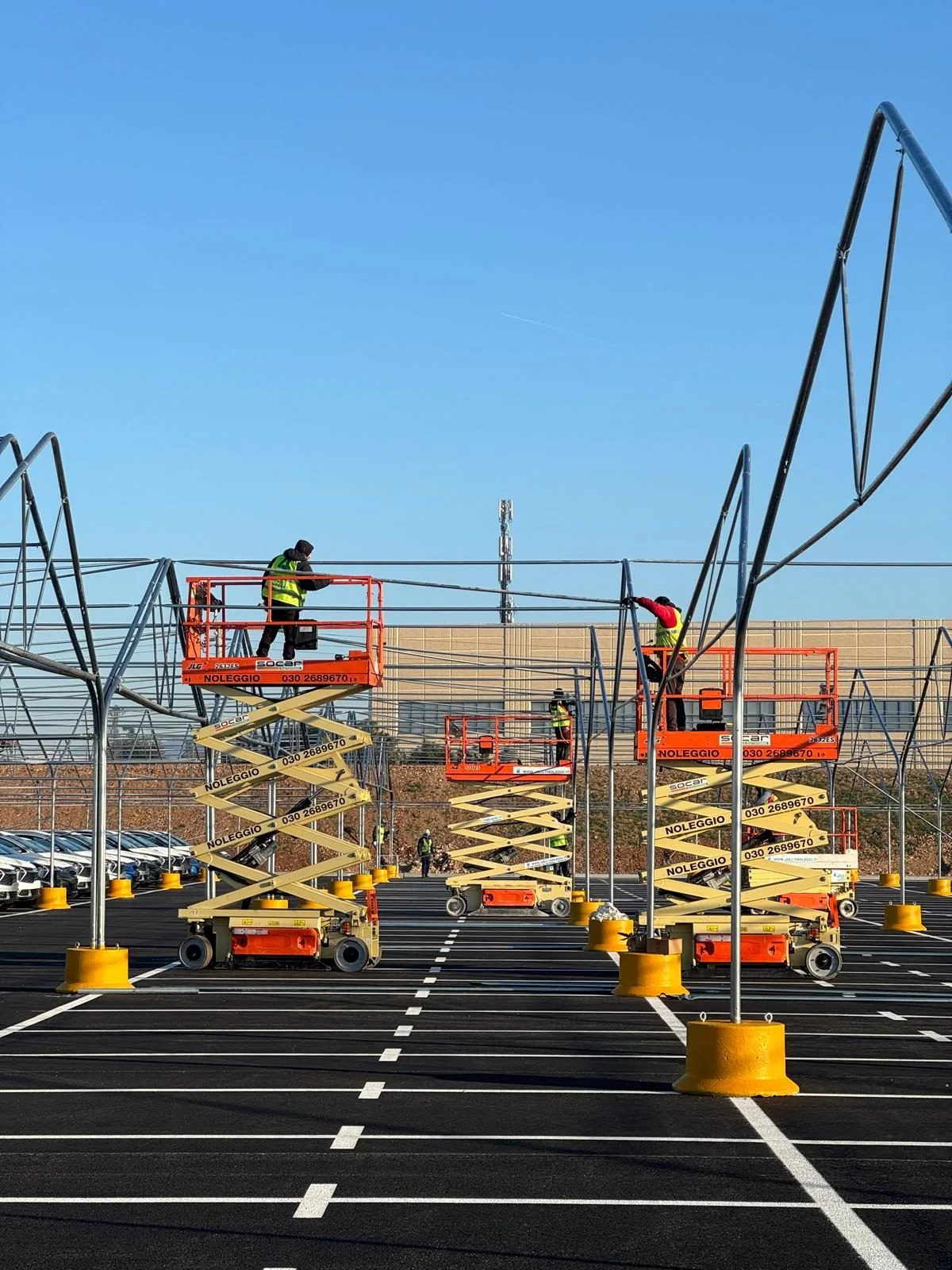 Équipes Euromet installant une grande couverture modulaire anti-grêle sur un parking logistique en activité